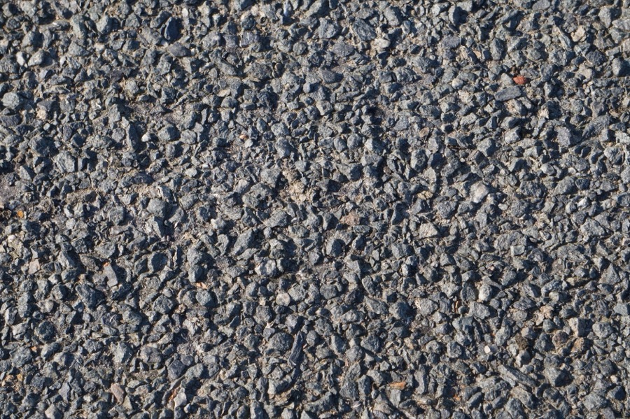 A detailed cross-section view of a gravel driveway, showing distinct layers of different aggregate sizes.
