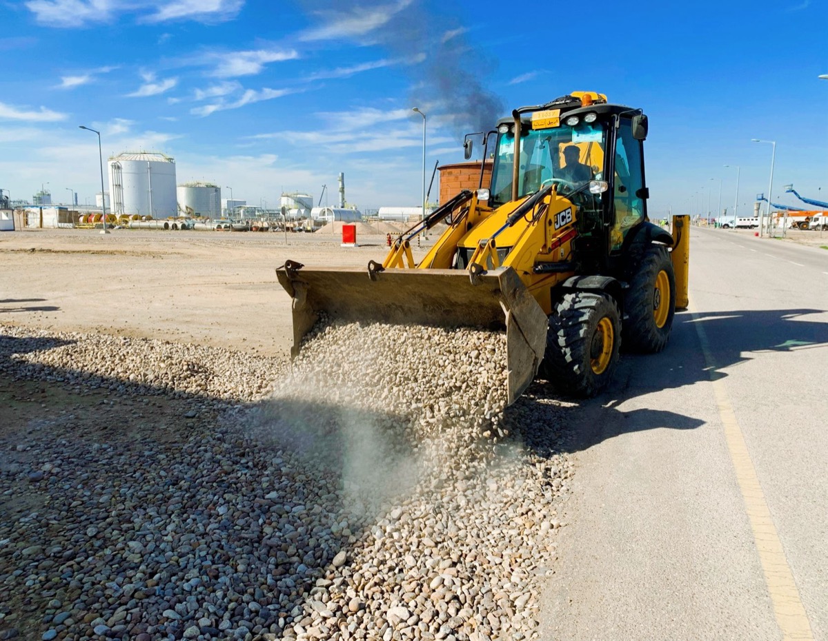 Heavy machinery such as a grader or compact roller working on preparing the sub-base for a new gravel driveway.