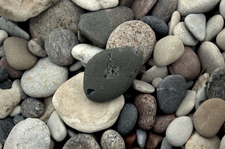 Various piles of gravel aggregate, showing different sizes and colors, ready for use as driveway material.