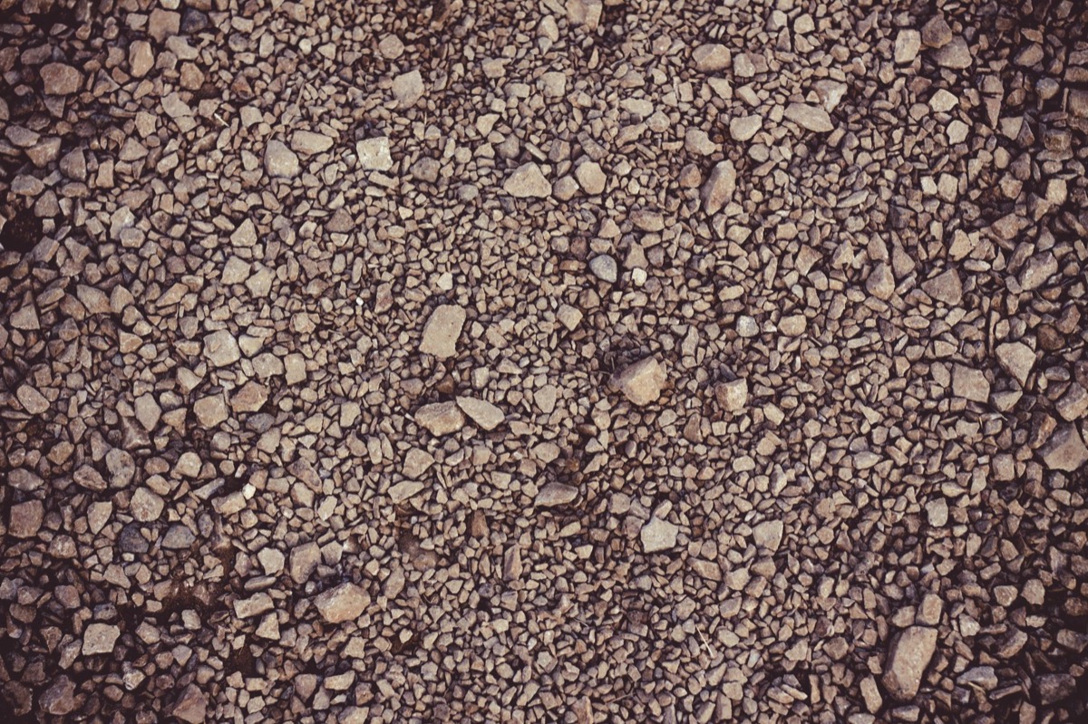 A wide shot of a newly installed gravel driveway, smoothly graded and bordered, with heavy machinery in the background.
