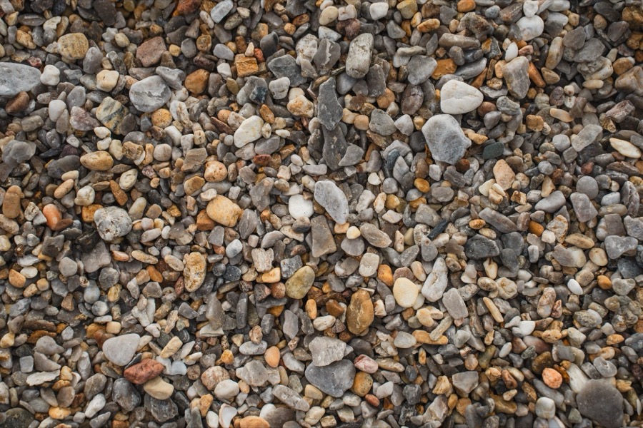 Close-up of various gravel aggregate types and sizes, used for driveways, laid out for comparison of material costs.