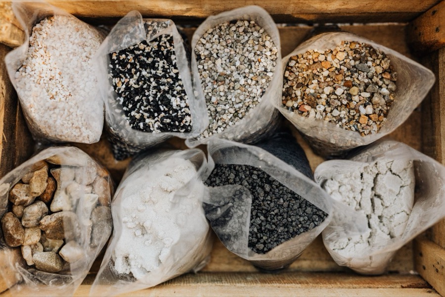Close-up of various sizes and colors of crushed stone aggregate samples on a surface, suitable for driveways.